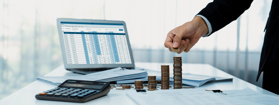 Corporate accountant use accounting software on laptop to calculate and maximize tax refunds and improve financial performance with business investment concept of growth stack coin in panorama. Shrewd