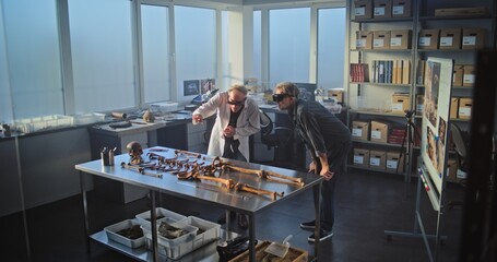 Two archaeologists conduct historical and scientific research in archaeological laboratory using...