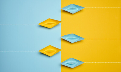 Paper boats on a yellow background, top view, representing the concept of unity and achieving...