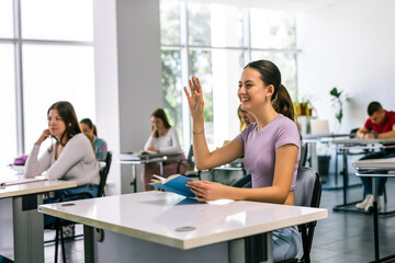Fototapeta premium Female student raising her hand in class to ask some question.