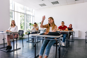 Female student raising her hand in class to ask some question