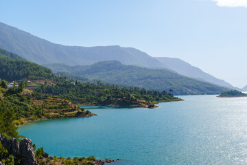 Fototapeta premium Water dam and reservoir river between green mountains under the blue cloudy sky