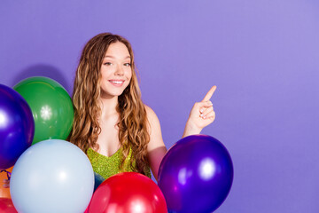 Fototapeta premium Photo portrait of lovely teen lady hold air balloons point empty space dressed stylish green garment isolated on violet color background