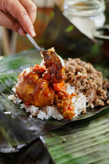 Mujer adulta sirve la preparación tradicional latinoamericana envuelta en hoja de plátano