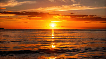 A beautiful sunset over a calm ocean with the sun dipping below the Horizon