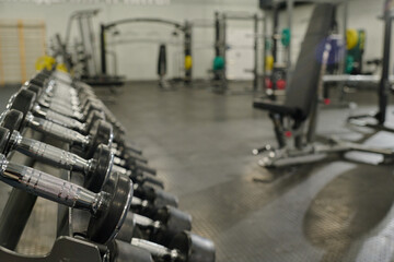Fototapeta premium Medium close up of metal rack with metal dumbbells in empty workout zone