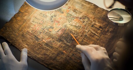 Two scientists examine ancient Egyptian papyrus together in archaeological lab. Team of...