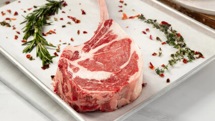 Closeup of raw tomahawk steak in a tray.