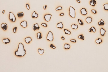 Burned  Torn, ripped paper pieces dot hole frame. Beige, brown copy space texture background