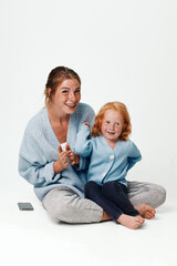 Family using technology together mother and daughter sitting on floor with cell phone in hands