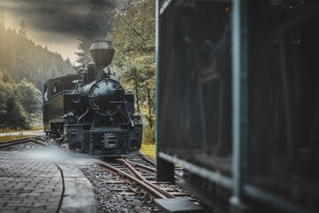 Historic steam locomotive in train station. Steam locomotive pump out clouds of smoke. Steam train with white smoke. Steam train on railway. Vintage steam train ride.