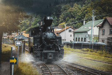 Historic steam locomotive in train station. Steam locomotive pump out clouds of smoke. Steam train with white smoke. Steam train on railway. Vintage steam train ride.