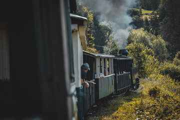 Historic steam locomotive in train station. Steam locomotive pump out clouds of smoke. Steam train with white smoke. Steam train on railway. Vintage steam train ride.