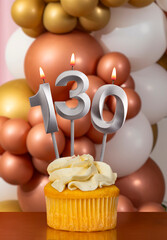 Cupcake with birthday candle on balloons background - Number 130