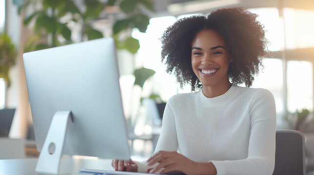 A vibrant image of a young, happy female businesswoman, smiling as she works at a desktop computer in a bright, modern office, engaging in a successful video call meeting with a cl