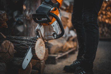 Cordless Chainsaw. Close-up of woodcutter sawing chain saw in motion, sawdust fly to sides. Chainsaw in motion. Hard wood working. Sawdust fly around. Firewood processing.