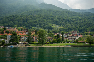Fototapeta premium Mandello del Lario, Italy - June 08, 2024: Como lake mountains. Small village on the middle ground.