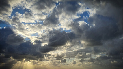 Fototapeta premium A stunning natural background showcasing dramatic clouds illuminated by the setting sun, with blue sky peeking through. Ideal for 4K wallpapers, banners, and natural-themed backdrops