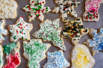 Frosted and decorated sugar cookies are on a baking sheet to dry.