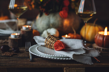 Atmospheric autumn elegant beautiful table setting with pumpkins for a wedding or thanksgiving family celebration. Fall decoration countryside rustic style, cozy home atmosphere , candles, wine