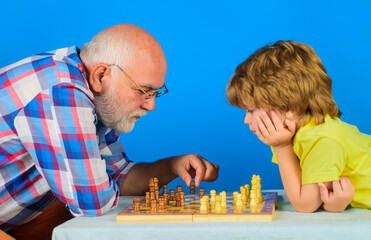 Chess competition. Grandfather and grandson playing chess. Senior man thinking about his next move in game of chess. Checkmate. Childhood and board game. Grandpa teaching his grandchild to play chess.