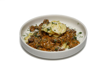 Stew with dried mushrooms and chips on a white plate.