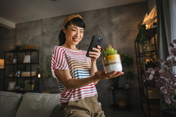 Mature japanese woman gardener take a photo of plant with mobile phone