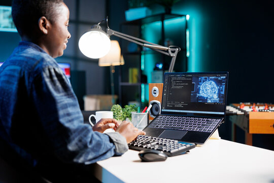 Female developer coding for AI and machine learning on digital laptop. Black woman looking at neural network and database on her personal computer while typing on the keyboard.