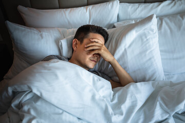 Sleepless man lying in bed feeling tired stressed 