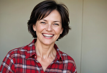 Fototapeta premium Portrait of a happy senior woman with short dark hair wearing a red and white plaid shirt , smiling to the camera. Generative Ai