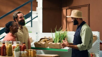 Shoppers at nearby zero waste green shop enquiring about organic cultivation and fresh vegetables kept in crates. Grocery store staff suggesting nutritious food selections to vegan couple.
