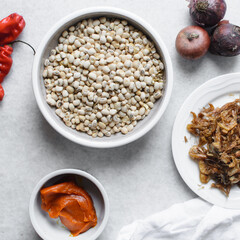 Overhead view of ingredients for making nigerian stewed beans on a granite countertop, top view of mise en place of ingredients for making ewa riro, process of making nigerian ewa riro