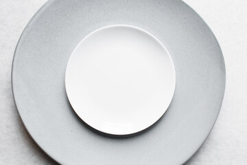 Top view of grey ceramic plates on a marble table, grey taupe ceramic minimalist plate