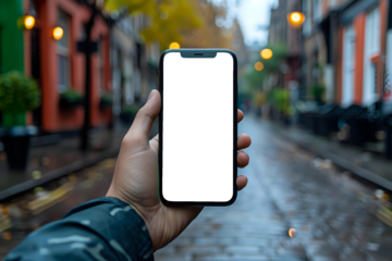 Hand holding a smartphone with a blank screen in an urban street setting on a rainy day. Ideal for app mockups, technology-related content, or lifestyle and urban-themed visuals.