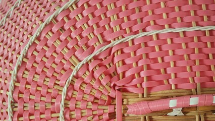 An intricate close-up of a pink and natural-toned woven material, creating a repetitive pattern and...