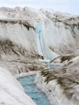 Drainage system on the surface of the ice sheet. The brown sediment on the ice is created by the rapid melting of the ice. Landscape of Greenland near Kangerlussuaq, Kingdom of Denmark.