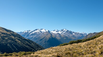 Fototapeta premium Majestic mountain range with snow-capped peaks and clear blue sky above. Majestic Mountain Range