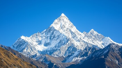 Obraz premium Majestic mountain range with snow-capped peaks and clear blue sky above. Majestic Mountain Range