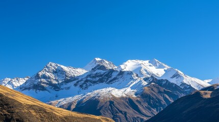 Fototapeta premium Majestic mountain range with snow-capped peaks and clear blue sky above. Majestic Mountain Range