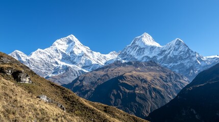 Fototapeta premium Majestic mountain range with snow-capped peaks and clear blue sky above. Majestic Mountain Range