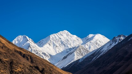 Majestic mountain range with snow-capped peaks and clear blue sky above. Majestic Mountain Range
