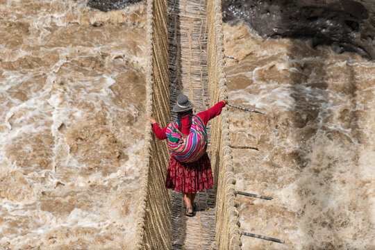 Quechua woman crossing Queshuachaca (Q'eswachaka) rope bridge, one of the last standing Incan handwoven bridges, Quehue, Canas Province, Peru