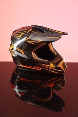 Modern motorcycle helmet with visor on mirror surface against pink background