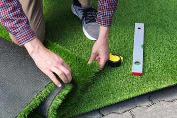Man installing artificial turf outdoors, closeup view