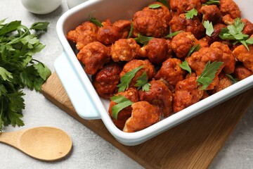 Baked cauliflower buffalo wings with parsley in baking dish on grey table
