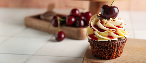Wooden board with sweet cherry cupcake and berries on white tile table