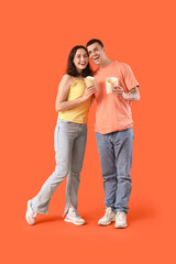 Beautiful young couple with french fries on orange background