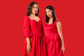 Beautiful young Asian women in stylish elegant outfits on red background