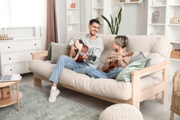 Obraz premium Private music teacher giving guitar lessons to little boy in living room