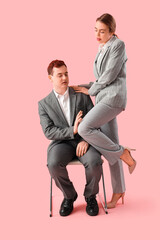 Business woman molesting her male colleague on pink background. Harassment concept